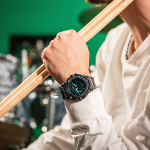 Casio G-Shock GA-2200SKL-8AER watch worn on wrist, lifestyle shot with drumsticks raised overhead