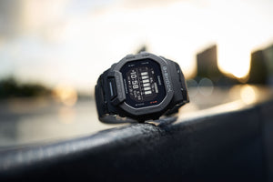 Casio G-Shock GBD-200-1DR watch propped outdoors at sunrise, lifestyle shot on a metal railing