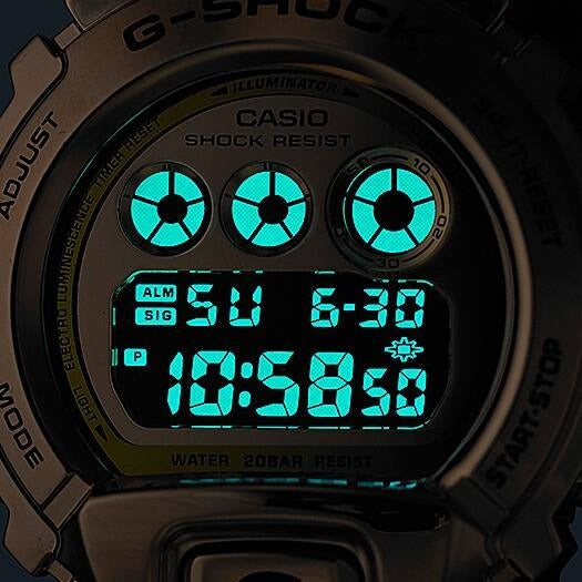 Casio G-Shock GM-6900G-9DR dial close-up with teal illuminator backlight glowing in the dark