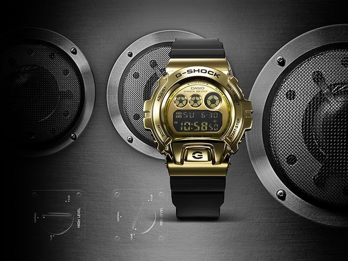 Casio G-Shock GM-6900G-9DR gold metal watch, front view styled with car speaker backdrop