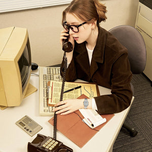 Casio Vintage LA680WA-7DF worn on wrist by a woman on a landline call at a retro office desk