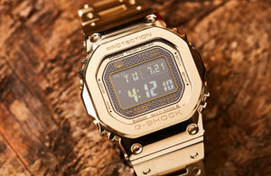 Casio G-Shock GMW-B5000GD-9DR Gold Stainless Steel Wristwatch Product shot with rock background 