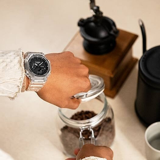 Casio G-Shock GA-2100SKE-7ADR watch worn on wrist reaching for a coffee bean jar, lifestyle shot