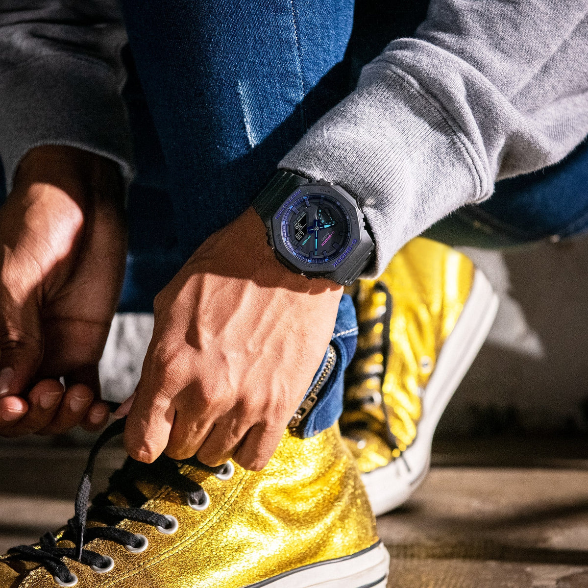 Casio G-Shock GA-2100VB-1AER worn on wrist while tying yellow sneakers, lifestyle shot