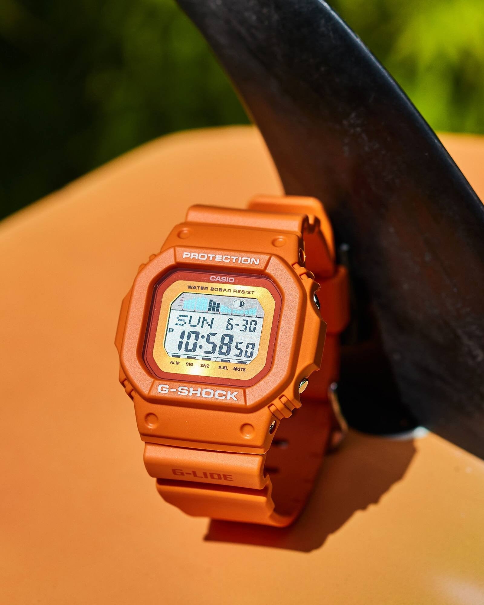 Casio G-Shock G-LIDE GLX-5600RT-4ER watch resting on an orange surfboard, close-up outdoor shot